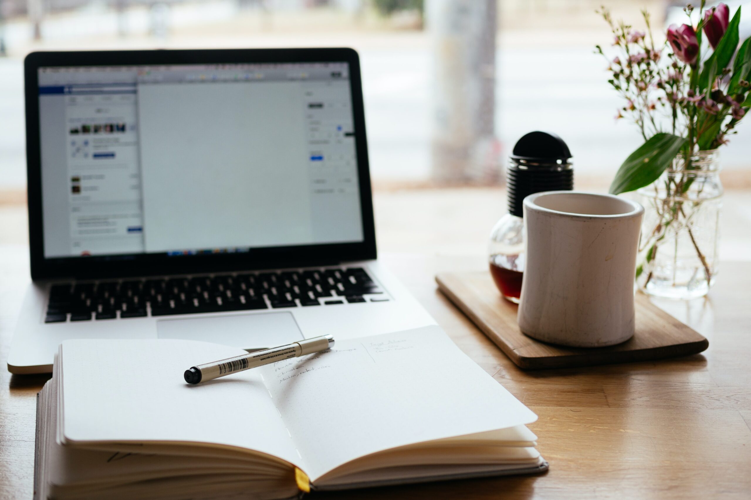 Photo of work desk with laptop, book and tea